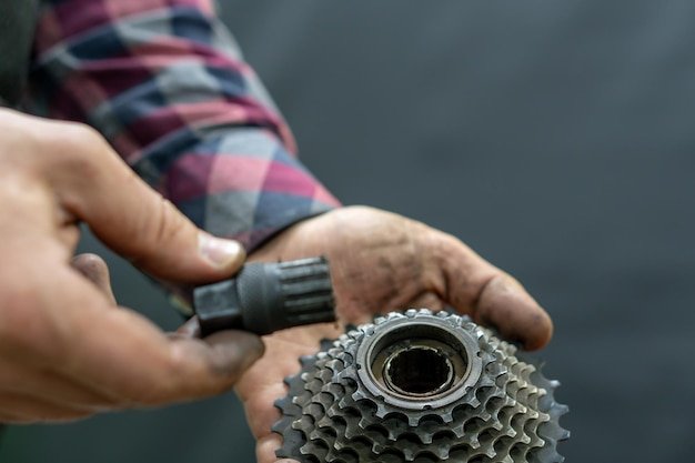 Repair of mountain and road bikes Mechanic's hands and a cassette closeup on a black background Replacement of wornout spare parts