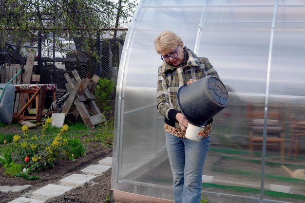Senior woman holding bucket while standing in garden