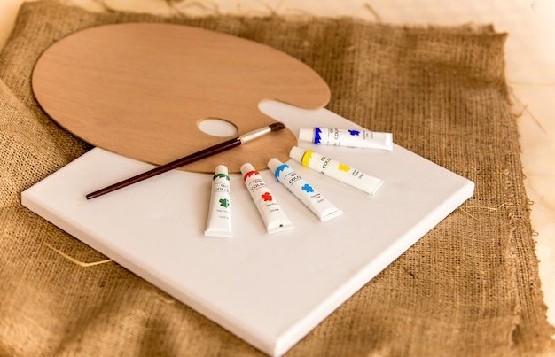 Tubes with oil paints and wooden pallet lying on table at art classroom