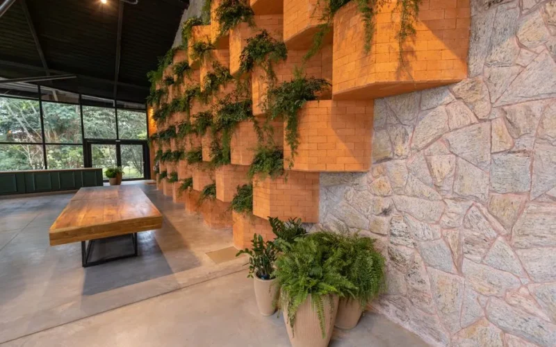 Spacious modern interior featuring brick walls with greenery and wooden table.