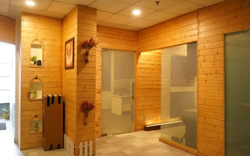 A cozy office space with wooden wall panels, illuminated by warm lighting and featuring modern glass doors.