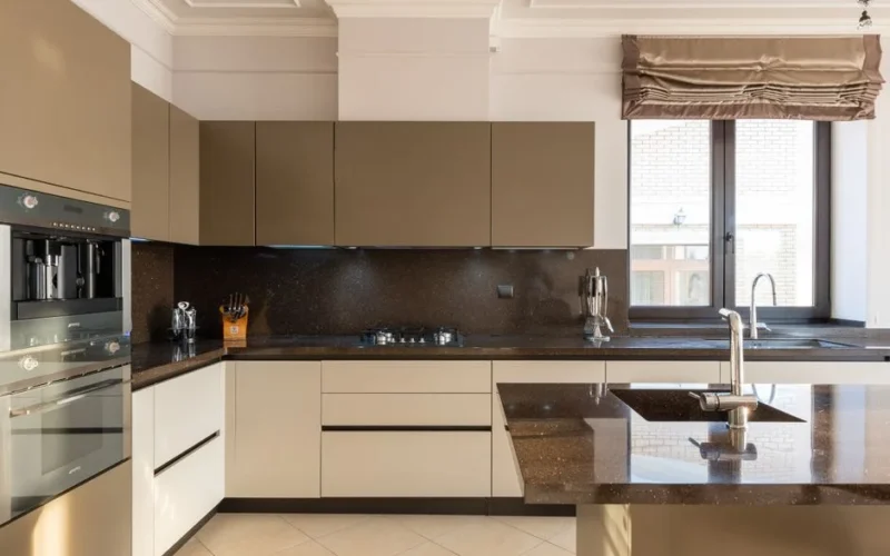 Table with tap placed in modern spacious kitchen with window and brown cupboards and contemporary appliances and various utensils at home