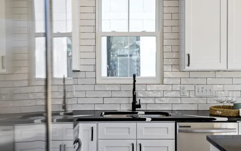 Sleek kitchen with black countertops, white cabinets, and modern design elements.