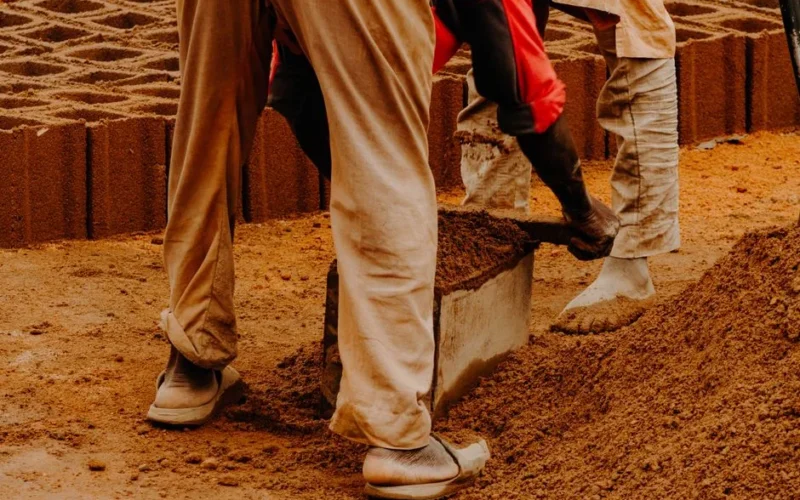 Workers using molds to shape eco-friendly bricks in an outdoor setting.