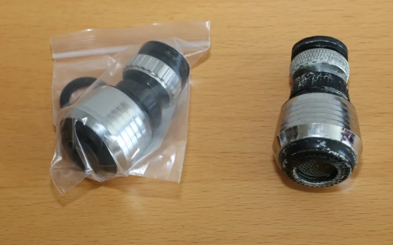 Two faucet aerators: new one in plastic bag and an old one with broken threading.