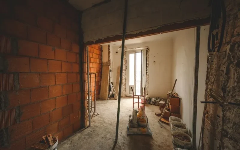A partially renovated room with exposed brick walls and construction materials on site.