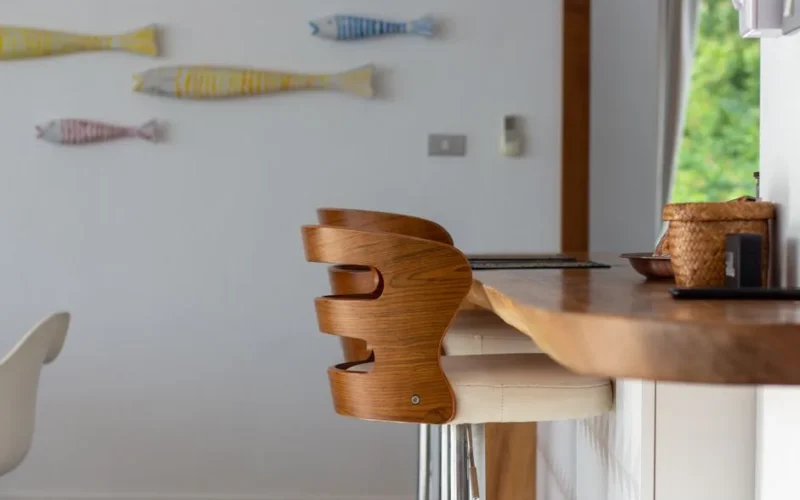 Contemporary kitchen interior featuring a wooden bar stool and decorative wall fish, offering a stylish and cozy ambiance.
