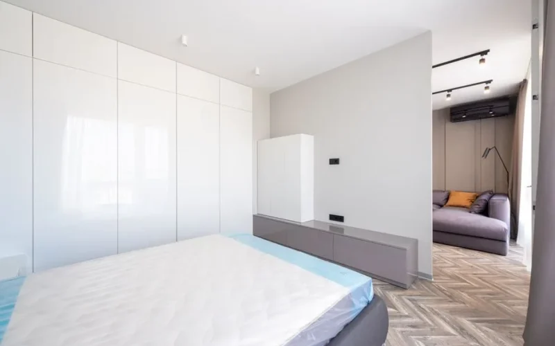 A bright minimalist bedroom with modern design features and an adjoining lounge area.