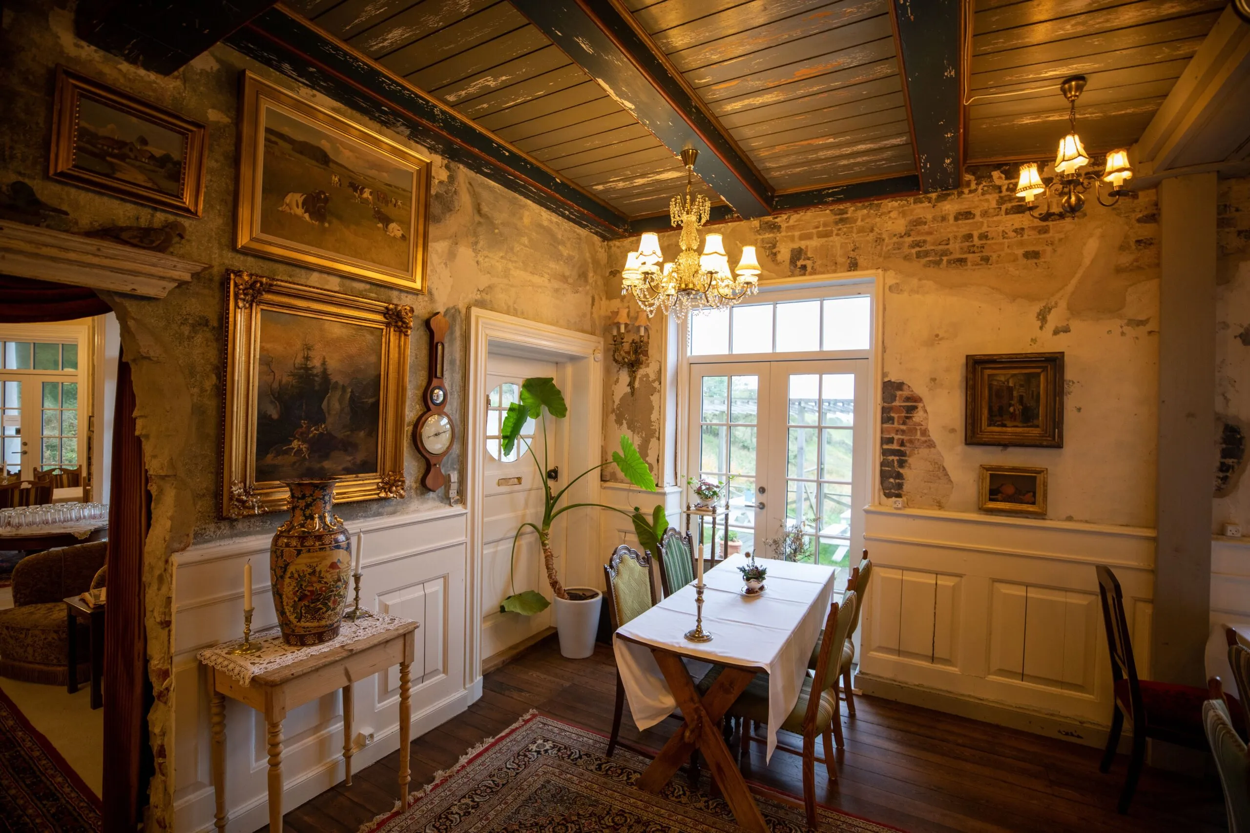 A cozy vintage dining room with art and rustic decor, featuring a chandelier and vintage furnishings.