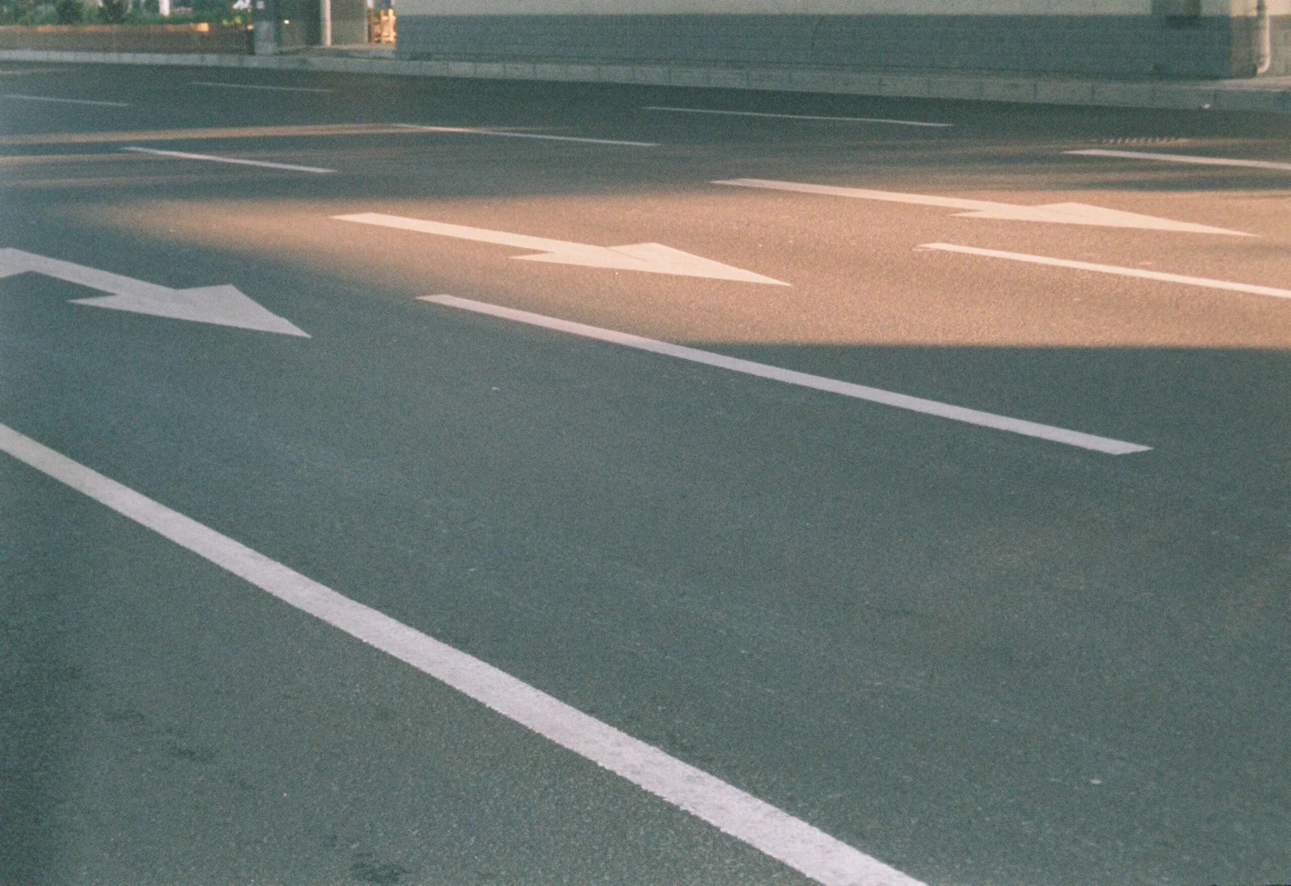 Photograph of a city street showing directional arrows on asphalt in sunlight.