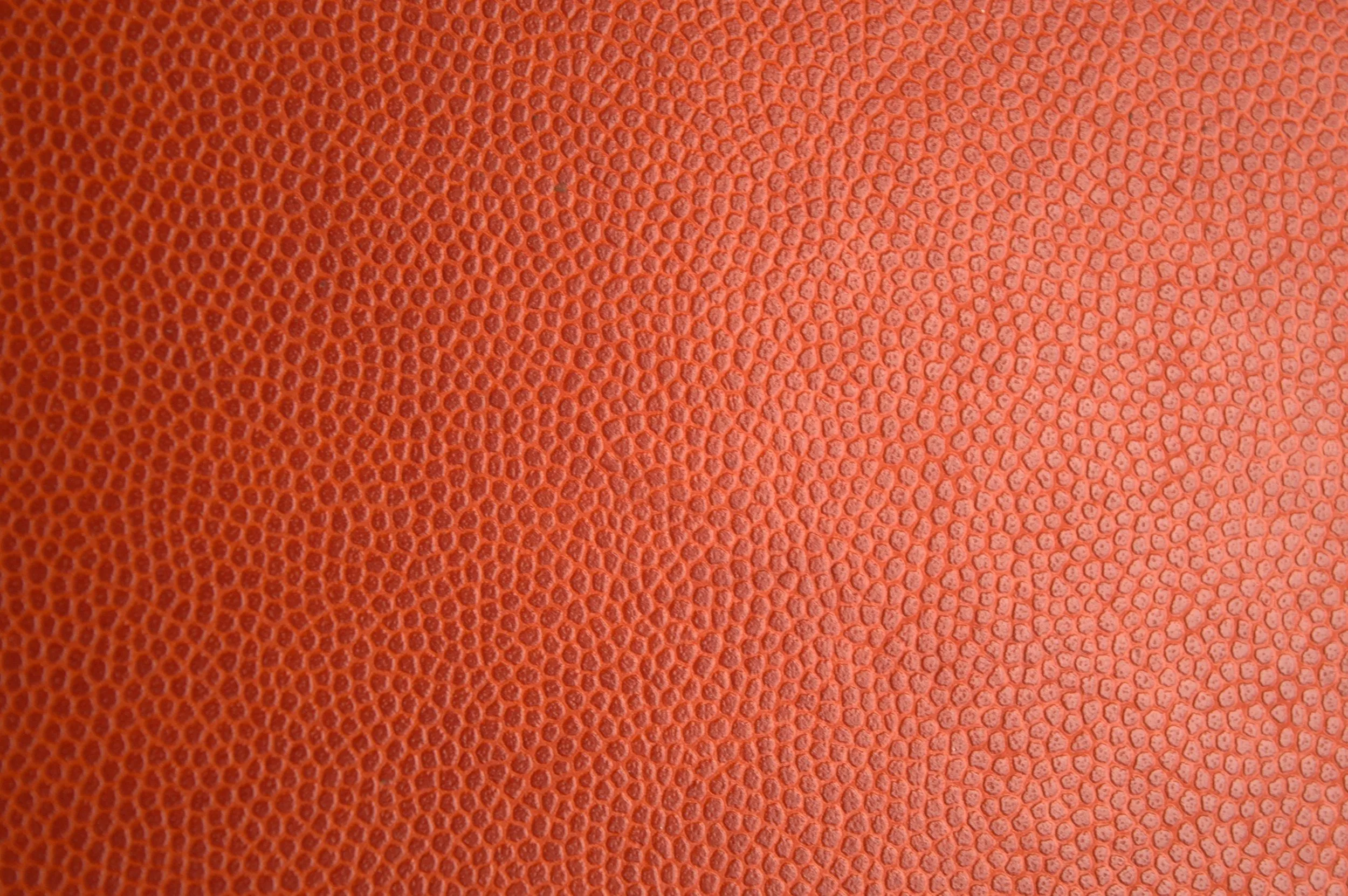 Detailed macro photo of orange leather texture, perfect for backgrounds or materials.