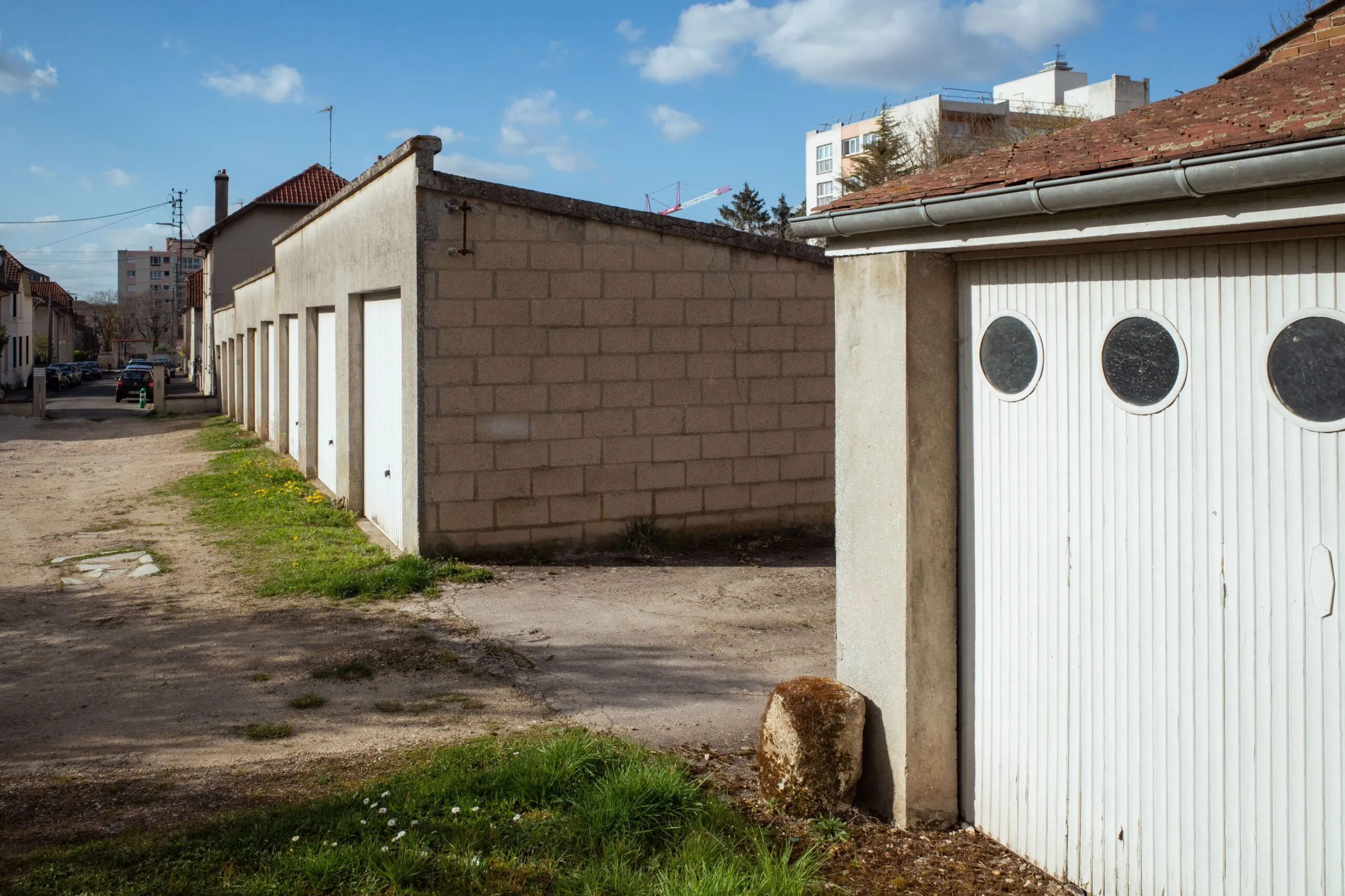 Street view of garages and urban buildings in Compiègne, Hauts-de-France, on a sunny day.