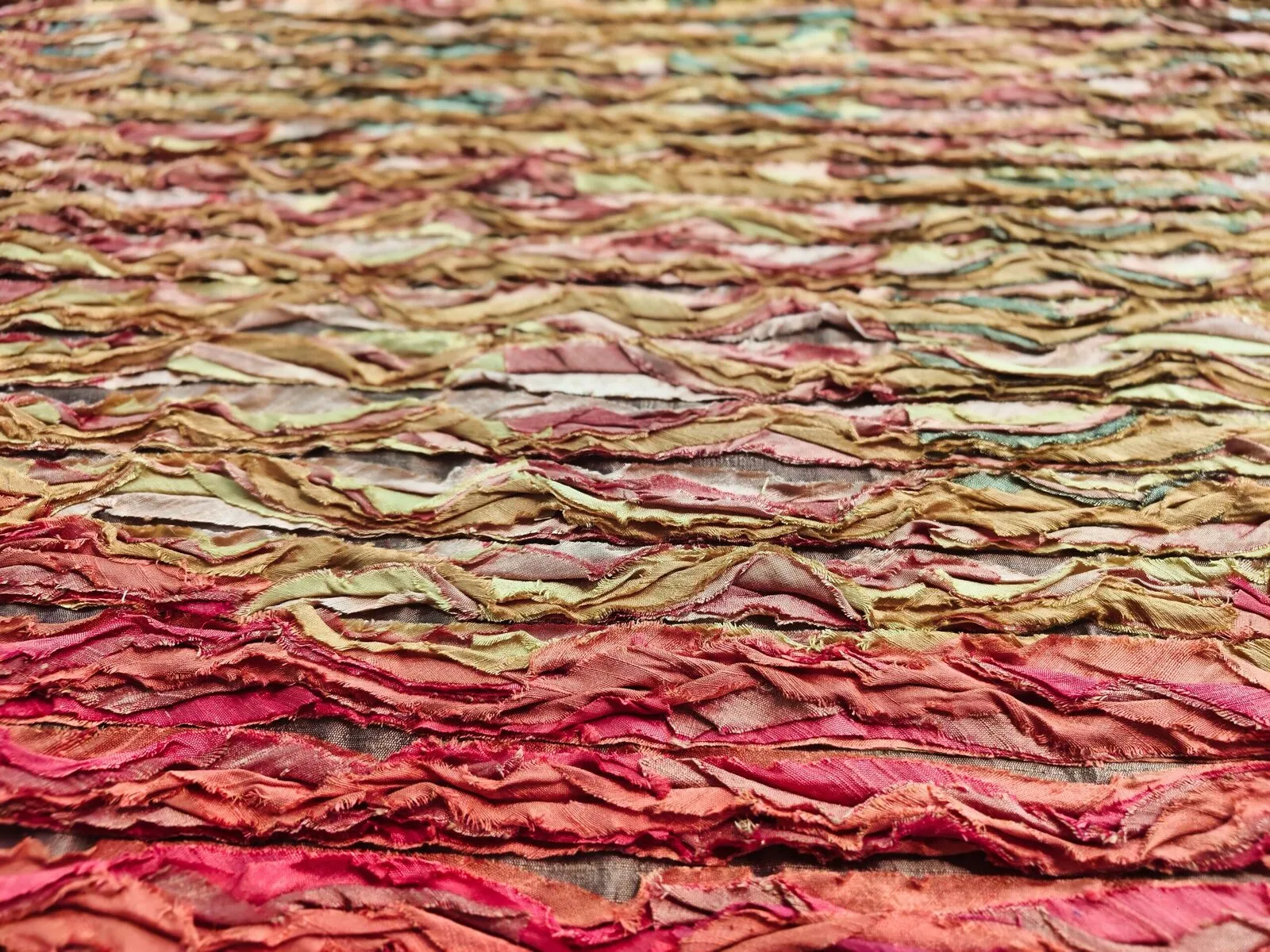 Colorful abstract textile art featuring layered and textured fabric swatches in warm tones.