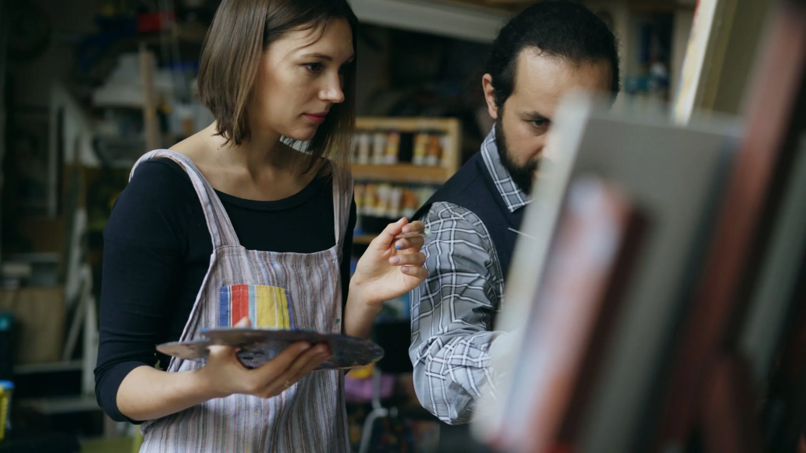 Two artists engaged in painting, focused on their creative process in a studio.