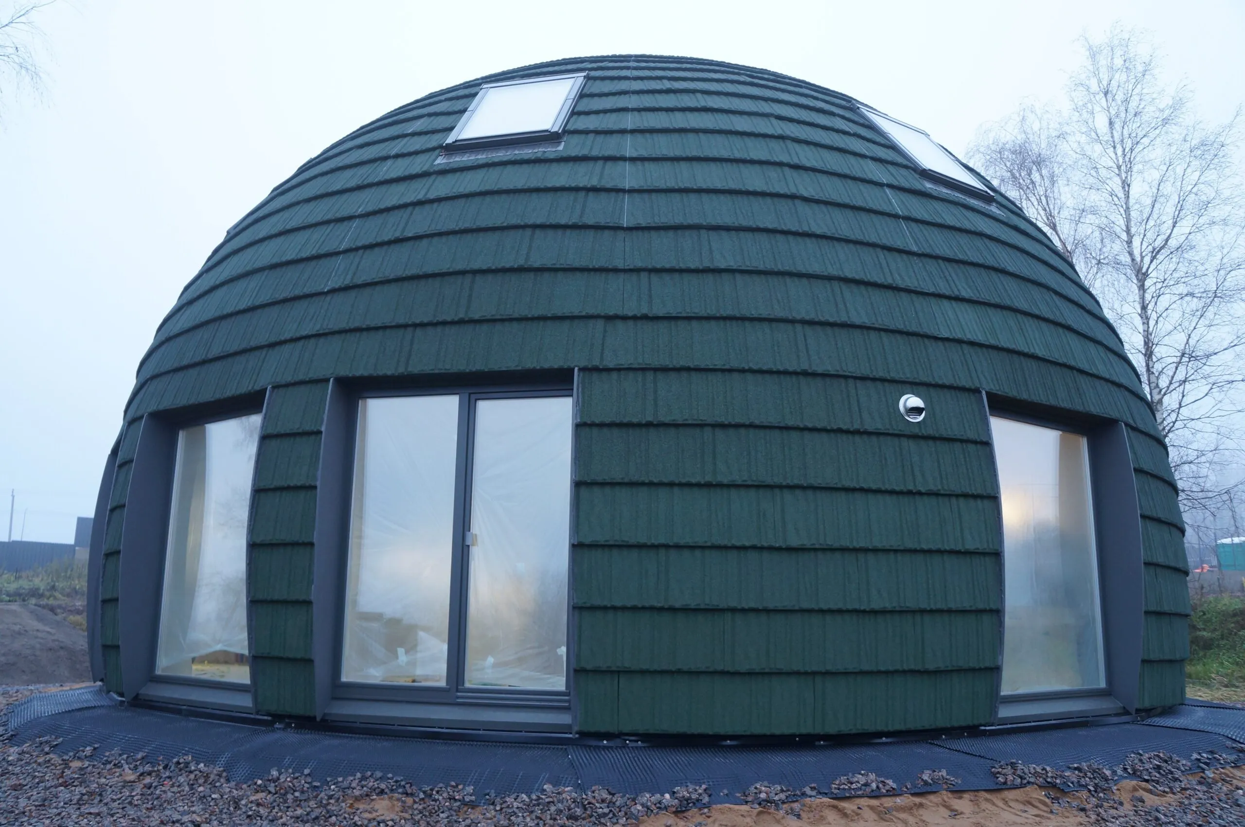 Unique green dome house on a foggy day, showcasing contemporary architecture.