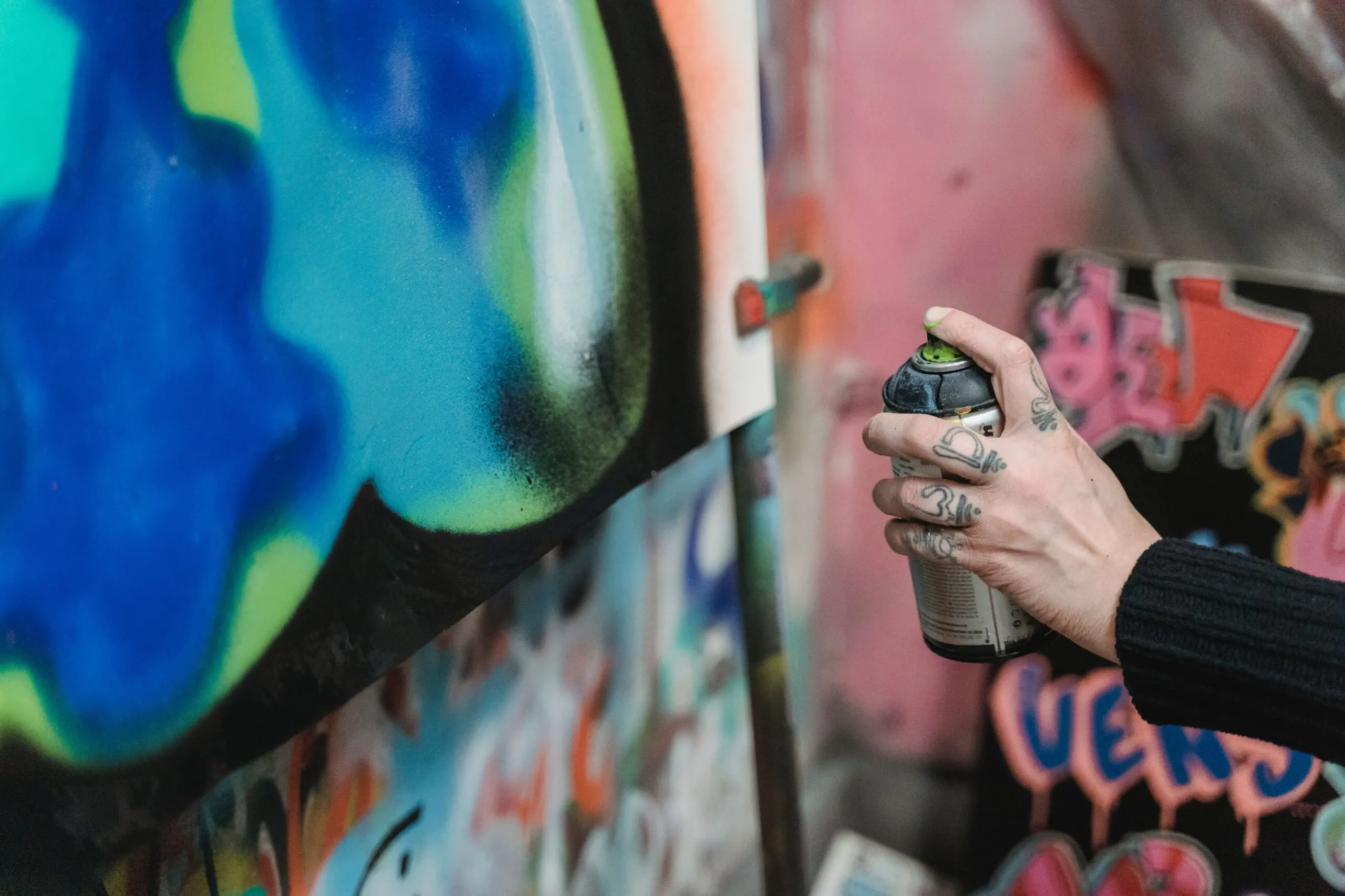 Close-up of an artist spray painting vibrant graffiti art on a wall.