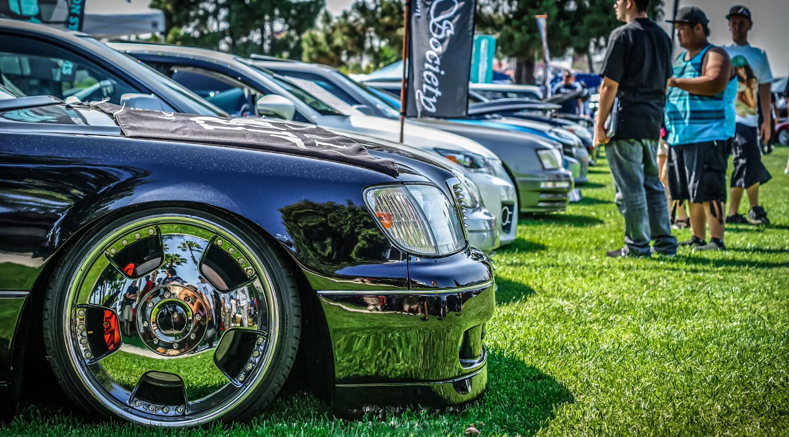 Showcase of custom cars with chrome detailing at an outdoor auto exhibition.