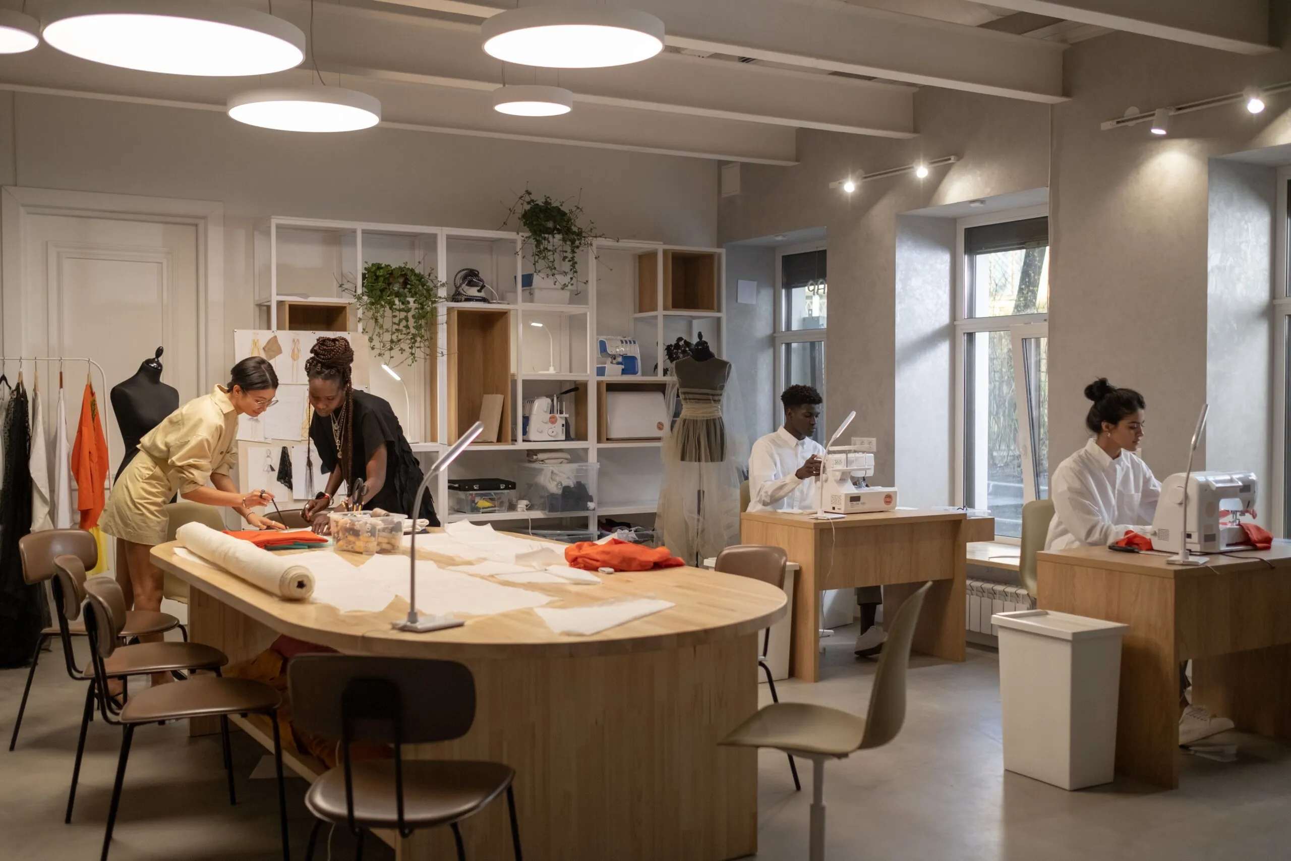 Fashion designers working together in a modern atelier with sewing machines and patterns.