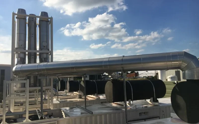 Modern industrial chimneys and support mast with flues against a clear blue sky, showcasing advanced infrastructure.