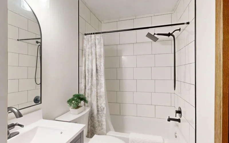 Sleek and clean modern bathroom with white tiles and black fixtures.