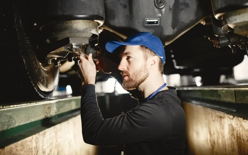 Auto mechanic working diligently on vehicle in workshop setting. Expertise in repair and maintenance.