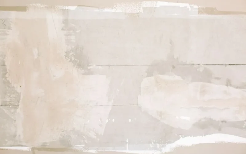 Close-up of an unfinished wall showing plaster and paint textures in a home renovation.