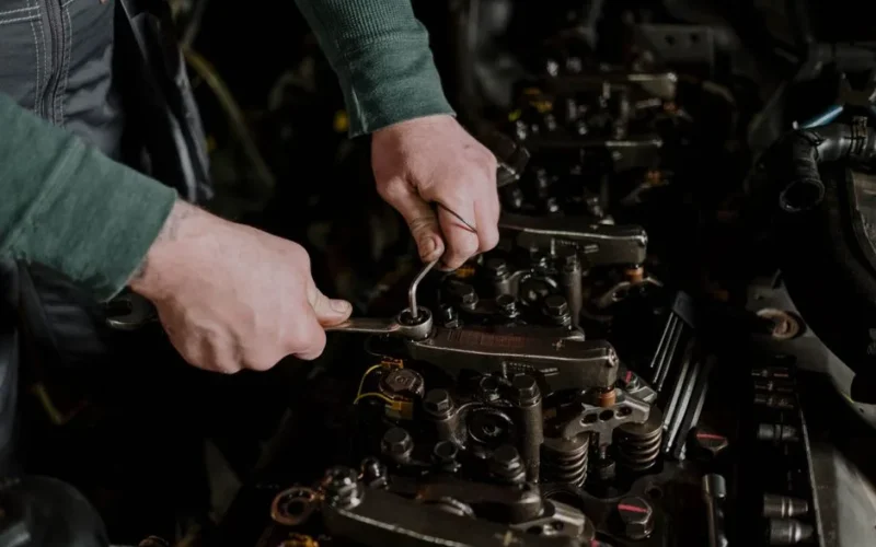 Close-up of a mechanic using hand tools to fix an engine, showcasing precision and skill.