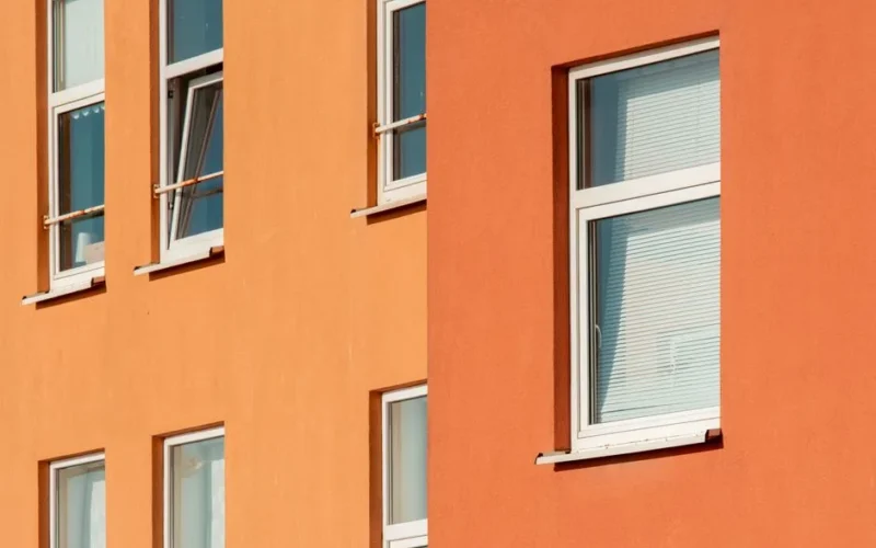 Close-up view of orange building exterior with multiple windows in urban setting.
