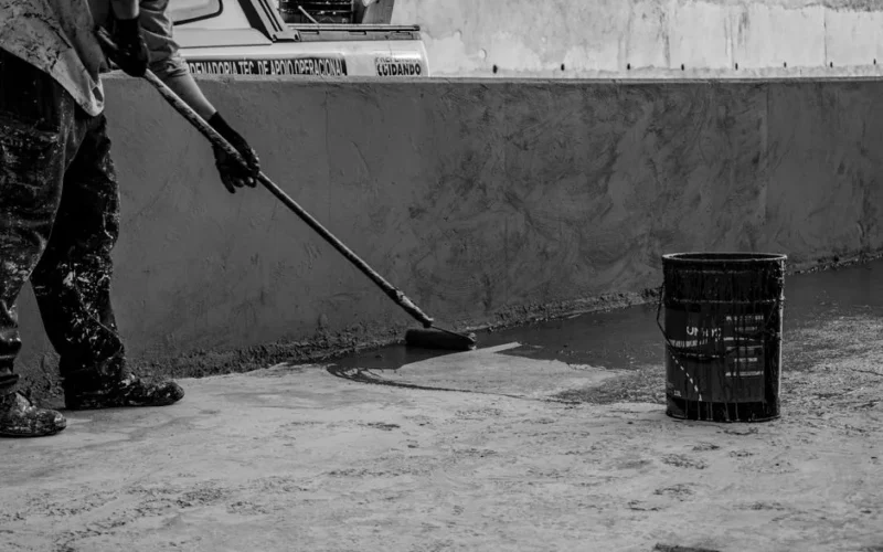 Black and white photo of a construction worker painting a wall outdoors in Londrina, Brazil.