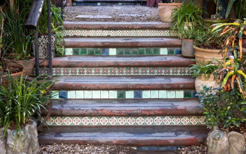 Decorative garden stairs adorned with colorful tiles and surrounded by lush potted plants.