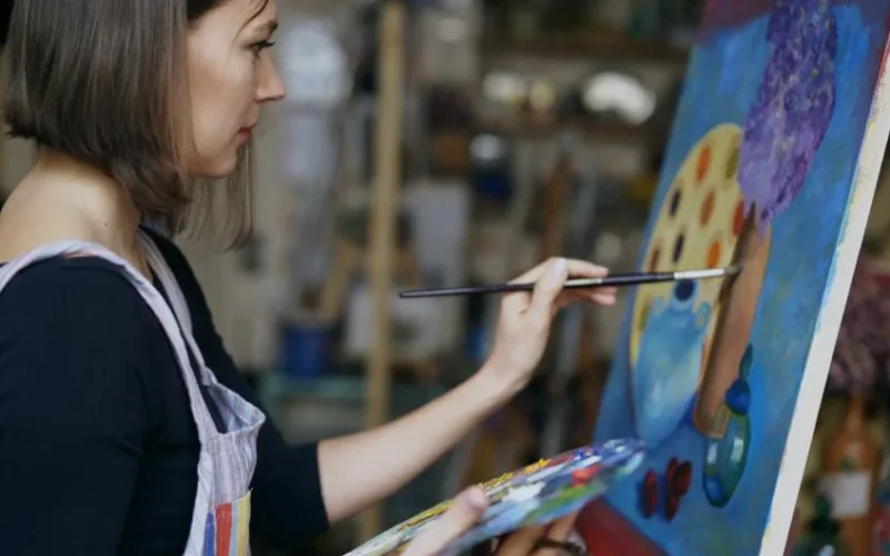 Woman artist painting colorful artwork in studio creating vibrant masterpiece.