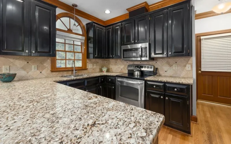 Sleek kitchen with dark cabinets, granite countertops, and stainless steel appliances.