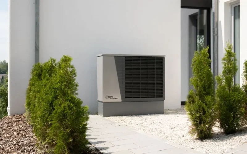 Outdoor air conditioner unit on a modern building surrounded by greenery and landscaping.