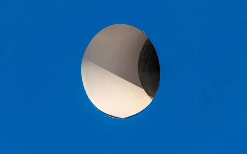 Close-up of a circle hole in a blue surface showing interior light and shadow play.