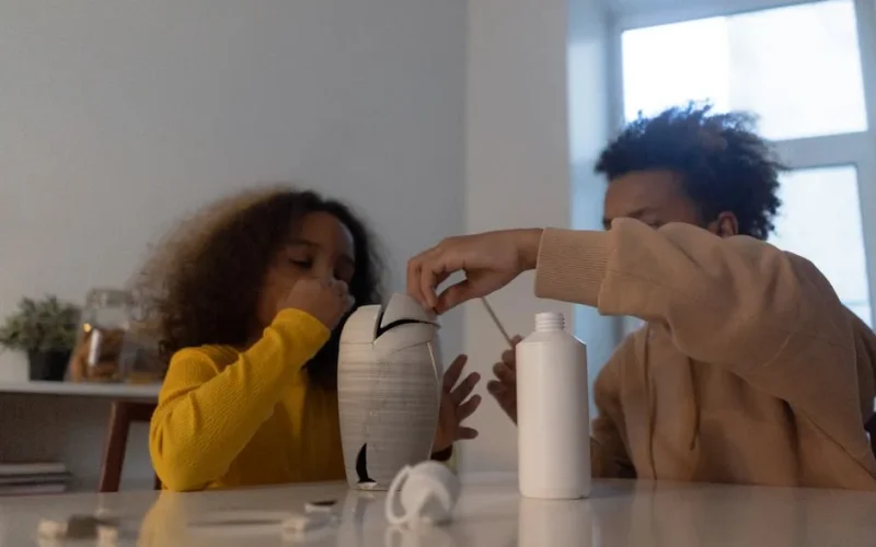 Two children fixing a vase at home, showcasing teamwork and creativity.