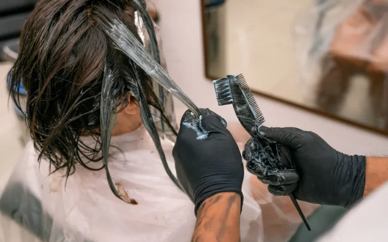 Close-up of hair coloring process in a salon. Hairdresser applying dye to client's hair.