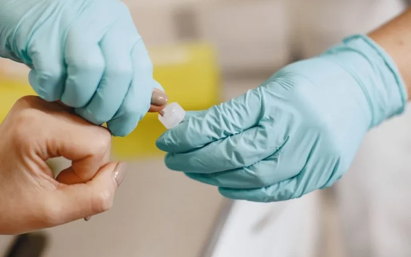 Close-up of a healthcare worker performing a blood test using sterile gloves.
