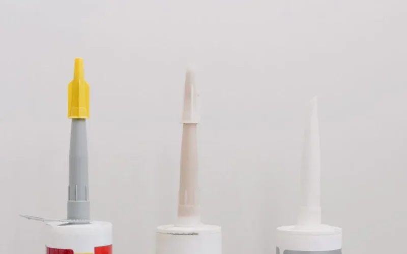 Set of various plastic tubes with glue for renovation works in workshop against white background