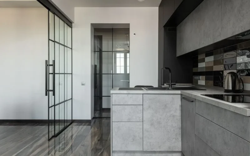 Contemporary kitchen featuring grey cabinets, glass partition, and marble elements.