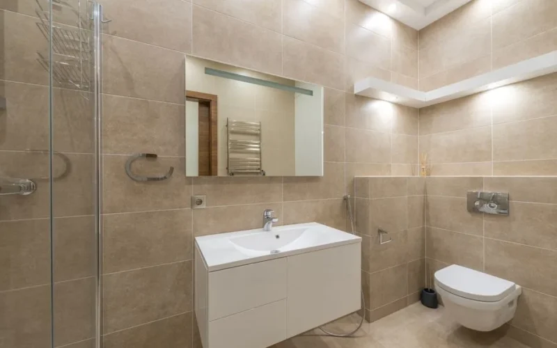 Elegant bathroom with modern fixtures and beige tiles.