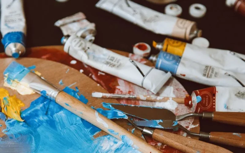 A close-up of a colorful artist's palette with paintbrushes and paint tubes, vibrant and inspiring.