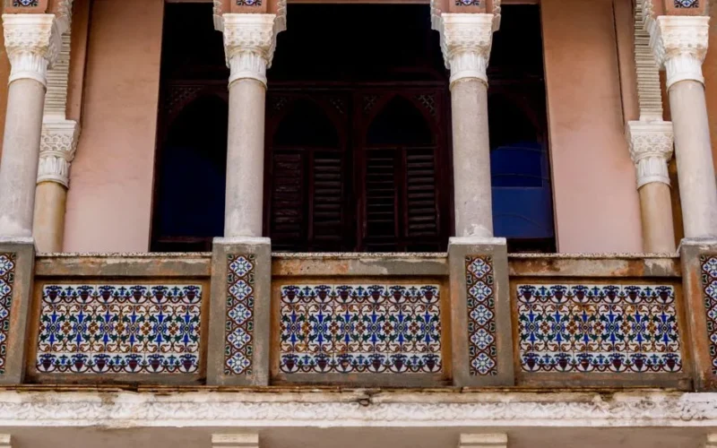 Close-up of a decorative balcony with colorful tiles and classical columns.