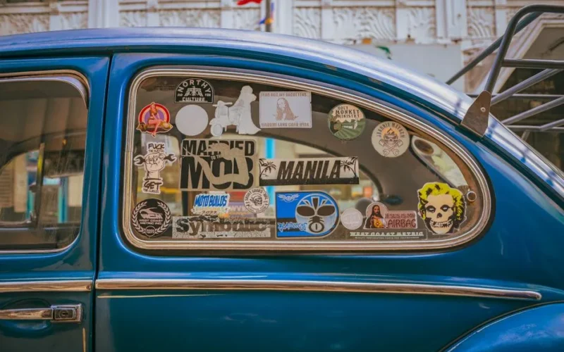 Close-up of a vintage car window adorned with various stickers in Manila, Philippines.