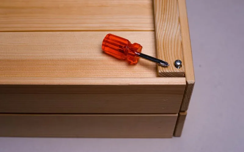 A close-up of a screwdriver on a wooden box, highlighting DIY and home improvement tools.