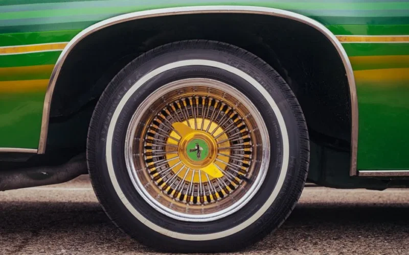 Detailed shot of a vintage car wheel with vibrant green and yellow colors.