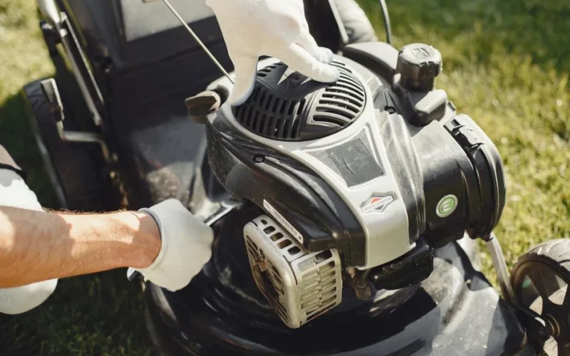 Hands in gloves adjusting a lawn mower outdoors, perfect for gardening themes.