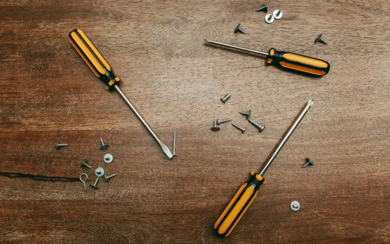 Flatlay of screwdrivers and screws on a wooden table, perfect for carpentry themes.
