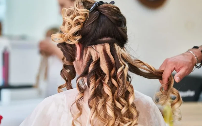 Close-up of hairstylist perfecting curls on a woman's hair in a salon setting.