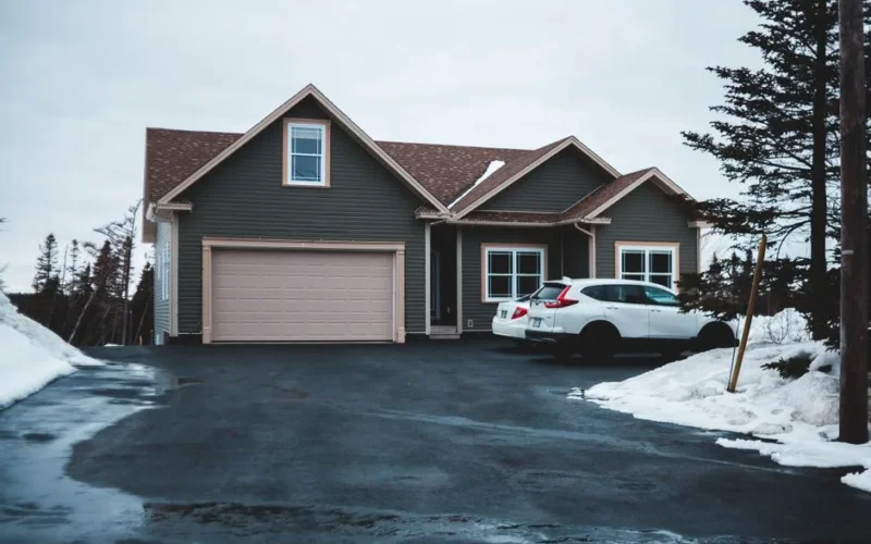 Exterior of small residential house in neighbourhood with cars parking on snowy ground in misty day
