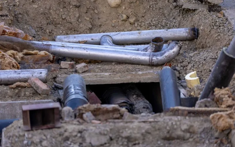 Close-up of urban pipe installation at a construction site, showing various pipes and materials.